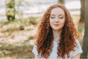 red haired woman looking peaceful in outdoor setting